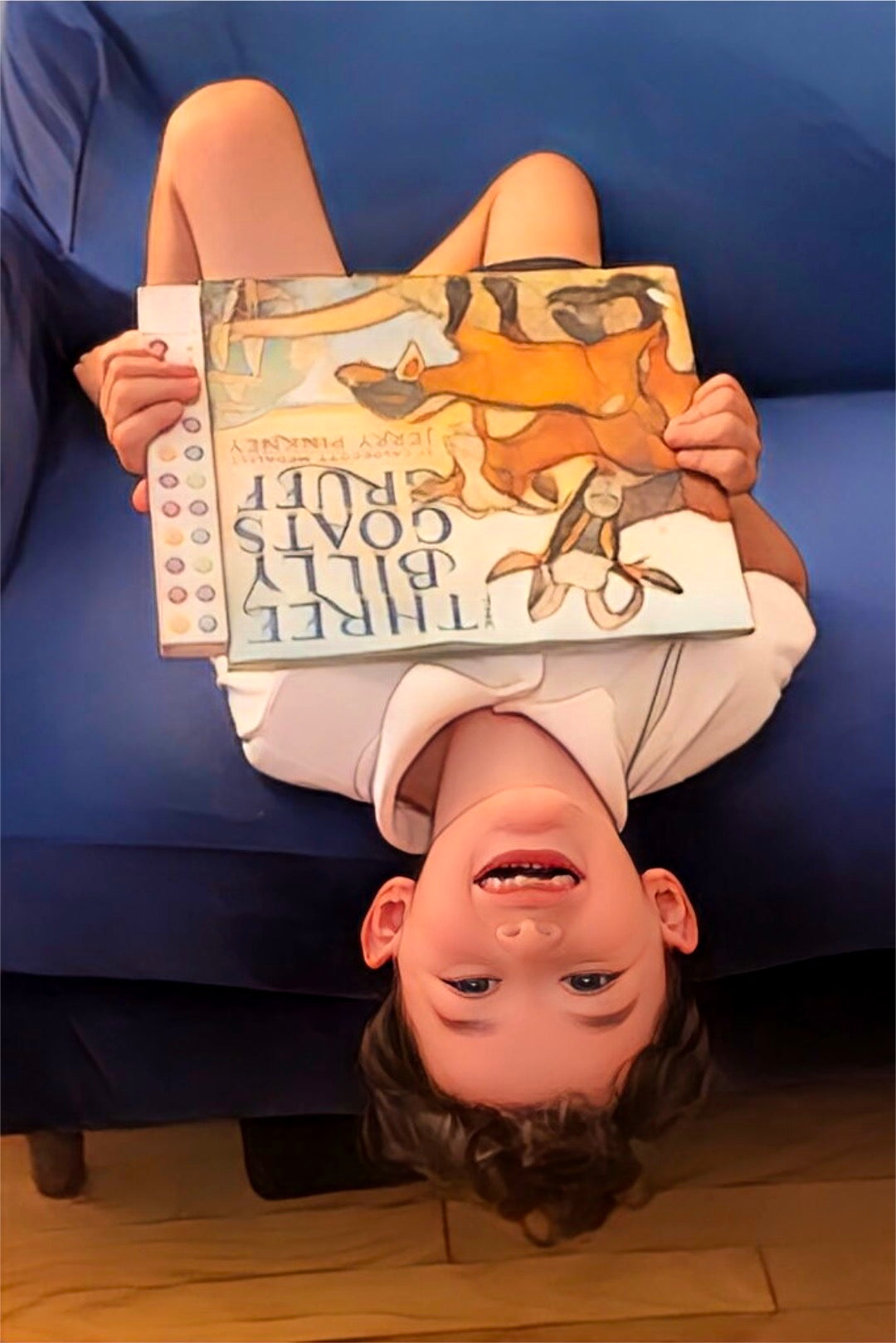 Boy upside down on sofa with Recordable Book Buddy and The Billy Goats Gruff